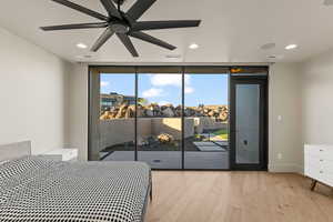 Bedroom with access to exterior, ceiling fan, light hardwood / wood-style floors, and a wall of windows