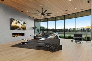 Living room with wooden ceiling, expansive windows, a fireplace, recessed lighting, and light wood-type flooring