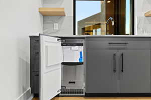 Detailed view of light wood-style floors, light countertops, open shelves, and gray cabinetry