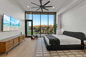 Bedroom with a wall of windows, light wood-style floors, ceiling fan, recessed lighting, and access to outside