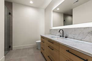 Bathroom featuring tile patterned flooring, vanity, an enclosed shower, and toilet