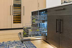 Kitchen view of beverage cooler, light wood-style flooring, dishwasher, light brown cabinetry, and modern cabinets