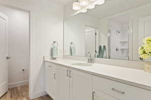 Bathroom with vanity, hardwood / wood-style flooring, and a shower with shower door