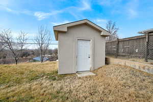 View of outdoor structure featuring a lawn