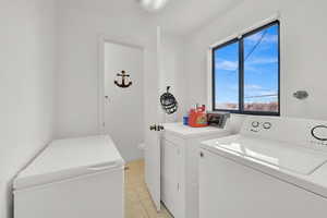 Clothes washing area featuring light tile patterned floors and independent washer and dryer