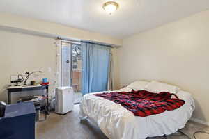 Bedroom with carpet flooring, a textured ceiling, and access to outside