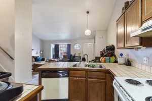 Kitchen with white appliances, tile countertops, and sink