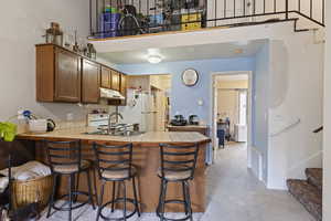 Kitchen with tile countertops, sink, decorative backsplash, a kitchen bar, and kitchen peninsula