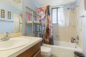 Full bathroom with toilet, vanity, and shower / tub combo with curtain