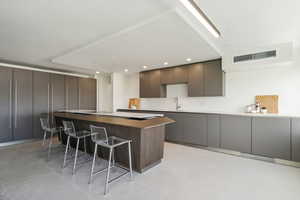 Kitchen featuring a kitchen breakfast bar, dark brown cabinets, sink, a center island, and light tile patterned flooring