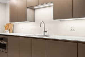 Kitchen with gray cabinetry, oven, and sink