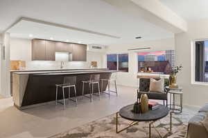 Kitchen with gray cabinetry, sink, light tile patterned floors, and a breakfast bar area