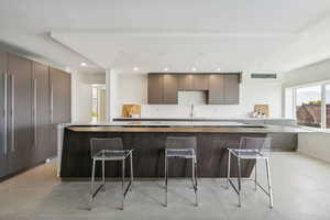 Kitchen featuring a kitchen breakfast bar, high quality fridge, sink, and a kitchen island