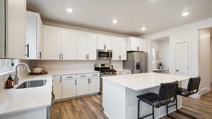 Kitchen featuring white cabinets, a center island, sink, and stainless steel appliances