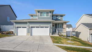 View of front of property featuring a front lawn, covered porch, and a garage