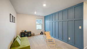 Loft featuring a board and batten wall treatment, light colored carpet, and a textured ceiling