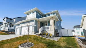 View of front facade with covered porch, a front yard, and a garage