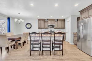 Kitchen featuring appliances with stainless steel finishes, pendant lighting, light hardwood / wood-style flooring, a notable chandelier, and a center island