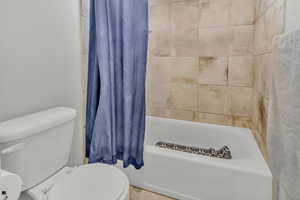 Bathroom with toilet and shower / bath combo with shower curtain