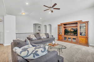 Living room with ceiling fan, vaulted ceiling, and light wood-type flooring