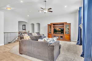 Living room with light hardwood / wood-style flooring, vaulted ceiling, and ceiling fan