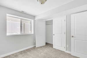 Unfurnished bedroom with light carpet and a closet