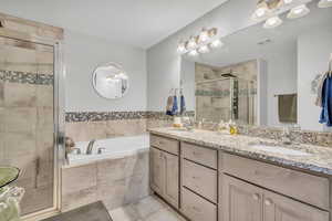 Bathroom featuring vanity, tile patterned flooring, and plus walk in shower