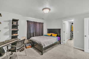 Carpeted bedroom featuring a walk in closet, a textured ceiling, and a closet