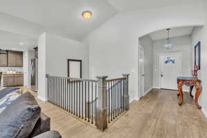 Hallway featuring vaulted ceiling and light hardwood / wood-style flooring