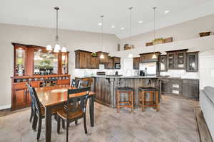 Tiled dining area with sink, high vaulted ceiling, and beautiful lighting.