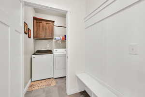 Mud room at entrance from garage has a bench and hooks. Washroom featuring washer & dryer, tile floor