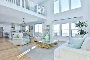 Living room with a chandelier, a high ceiling, and light hardwood / wood-style floors