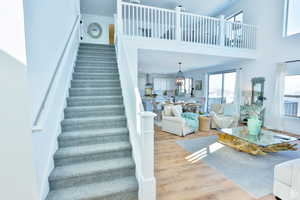 Staircase with hardwood / wood-style flooring and a towering ceiling