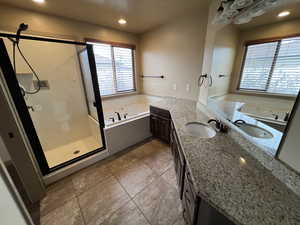 Bathroom featuring tile patterned flooring, vanity, and shower with separate bathtub