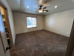 Carpeted spare room featuring a textured ceiling, ceiling fan, and lofted ceiling