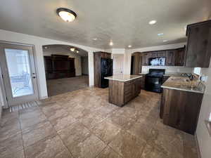 Kitchen featuring a center island, black appliances, sink, ceiling fan, and dark brown cabinets