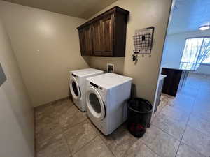 Washroom with cabinets and washer and clothes dryer