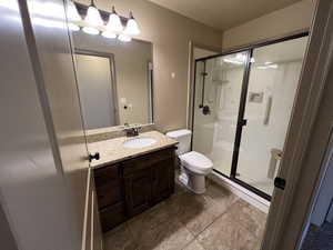 Bathroom featuring tile patterned floors, vanity, toilet, and a shower with shower door