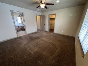 Unfurnished bedroom with a spacious closet, ceiling fan, ensuite bathroom, light carpet, and a closet