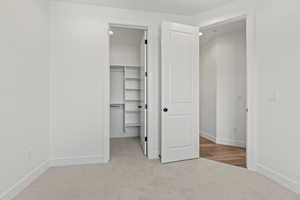 Unfurnished bedroom with light colored carpet and a closet