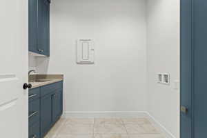 Laundry area featuring washer hookup, light tile patterned flooring, cabinets, and sink