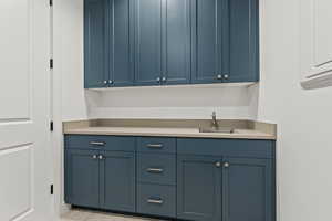 Interior space featuring blue cabinetry, light tile patterned floors, sink, and electric panel