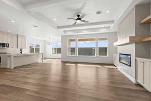 Unfurnished living room featuring sink, ceiling fan with notable chandelier, and light wood-type flooring