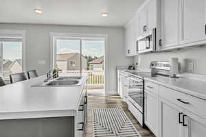 Kitchen featuring stainless steel appliances, sink, a center island with sink, white cabinets, and a breakfast bar area