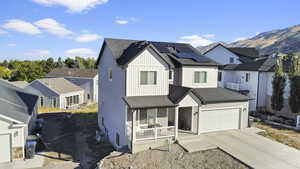 View of front facade with solar panels, a mountain view, cooling unit, a garage, and a porch