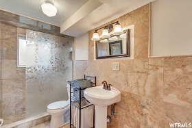 Bathroom featuring a textured ceiling, tile walls, and toilet