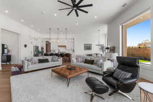 Living room with ceiling fan with notable chandelier and light hardwood / wood-style floors