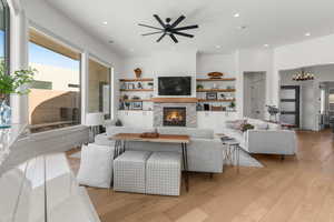 Living room featuring a stone fireplace, light hardwood / wood-style floors, and ceiling fan with notable chandelier