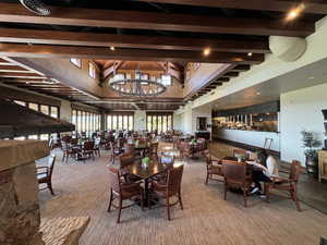 Dining area with beam ceiling, a towering ceiling, carpet floors, and a notable chandelier