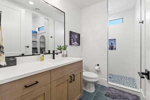 Bathroom featuring tile patterned floors, vanity, toilet, and walk in shower